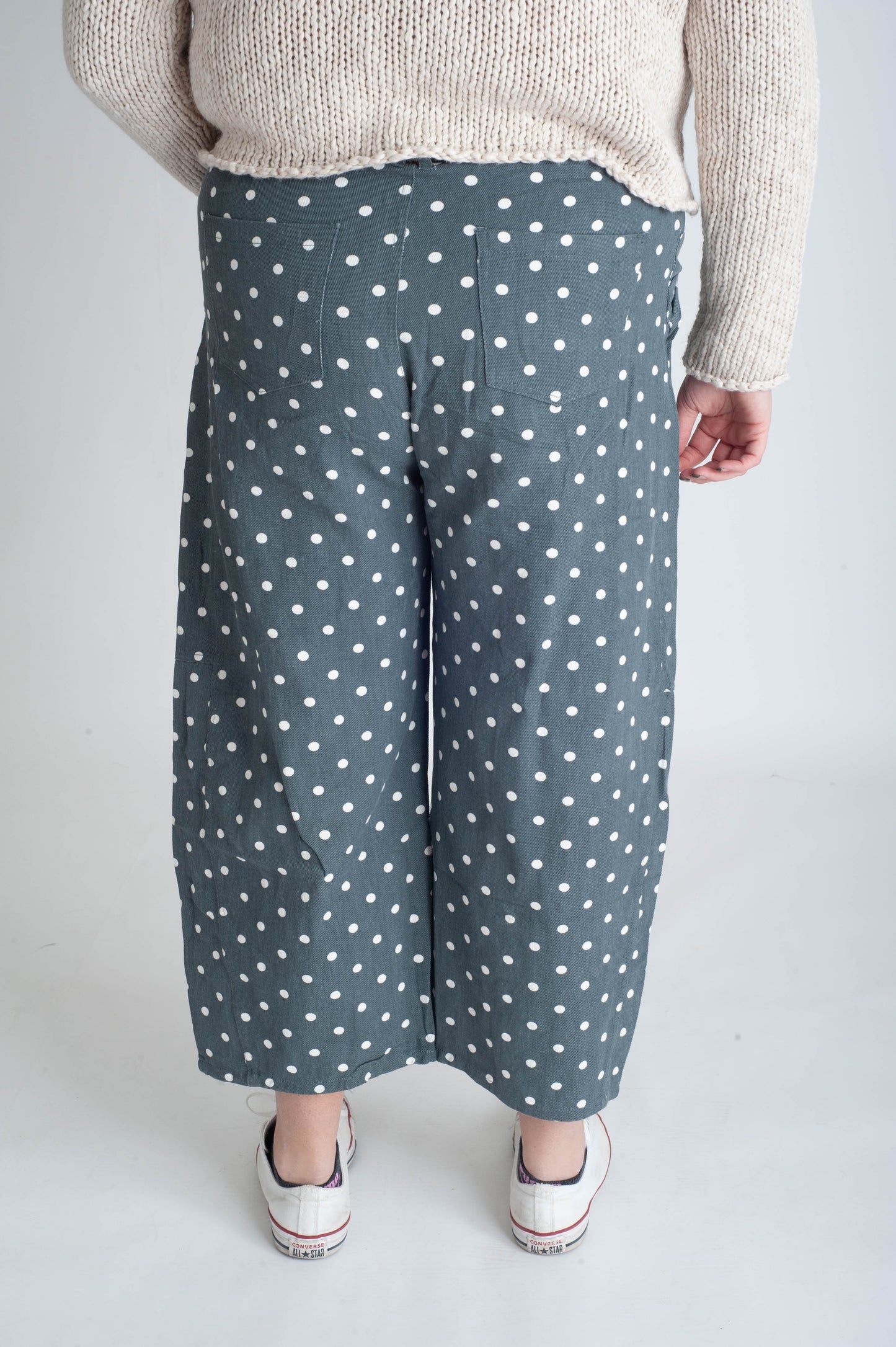 Person wearing blue polka dot pants on a plain background