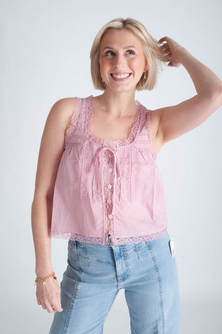 Woman wearing a pink sleeveless top and blue jeans against a white background