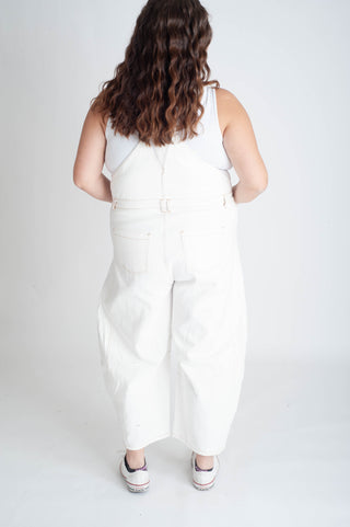 Person wearing a white sleeveless top and pants set on a plain background
