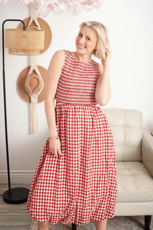 Woman wearing a red and white checkered dress in a living room setting.