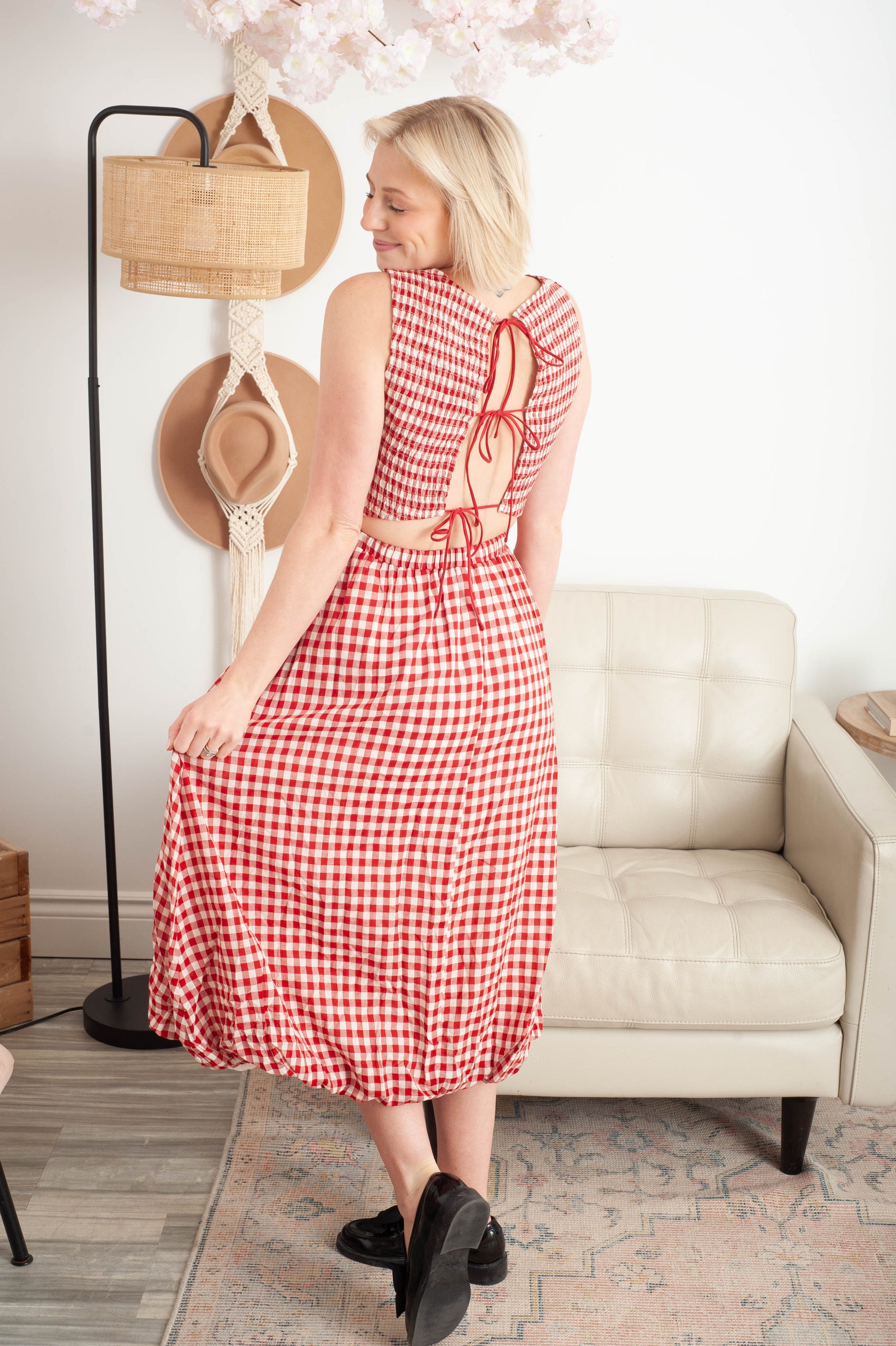 Woman in a red checkered dress standing in a living room.