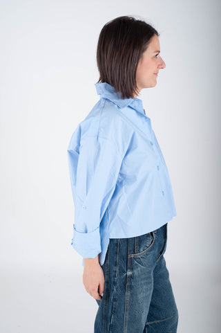 Woman wearing a light blue shirt and jeans on a white background
