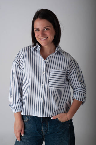 Woman wearing a striped shirt and jeans against a plain background