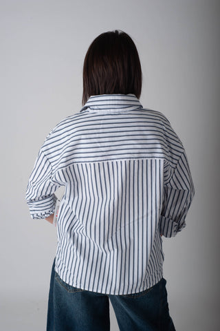 Person wearing a striped shirt and jeans against a plain background