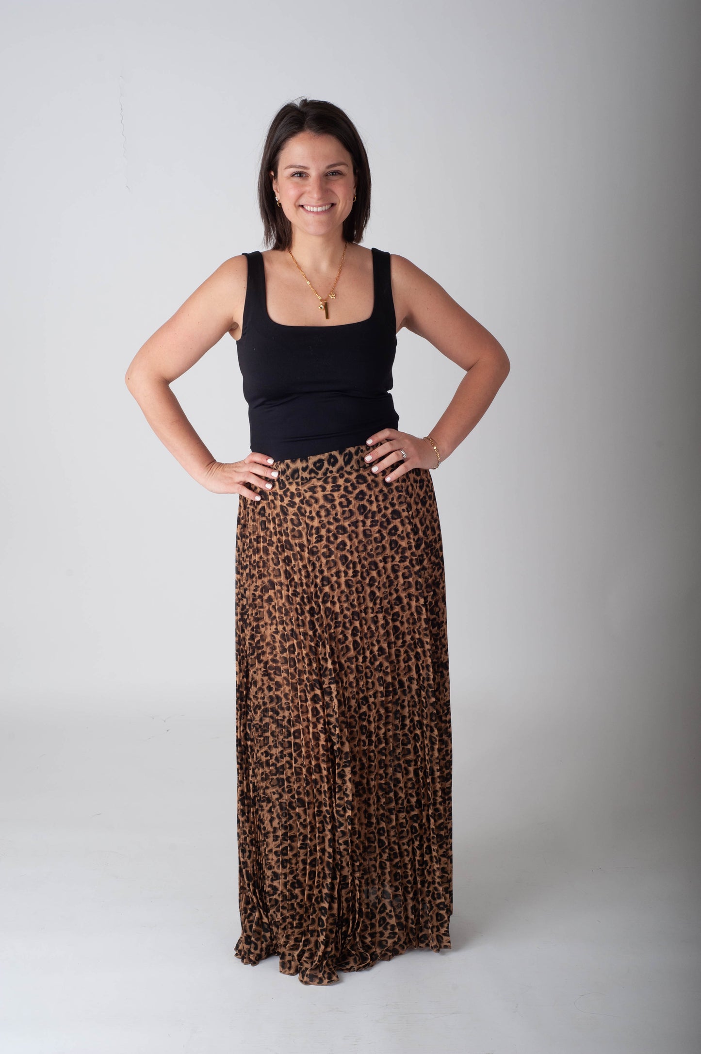 Woman wearing a black tank top and leopard print skirt on a white background
