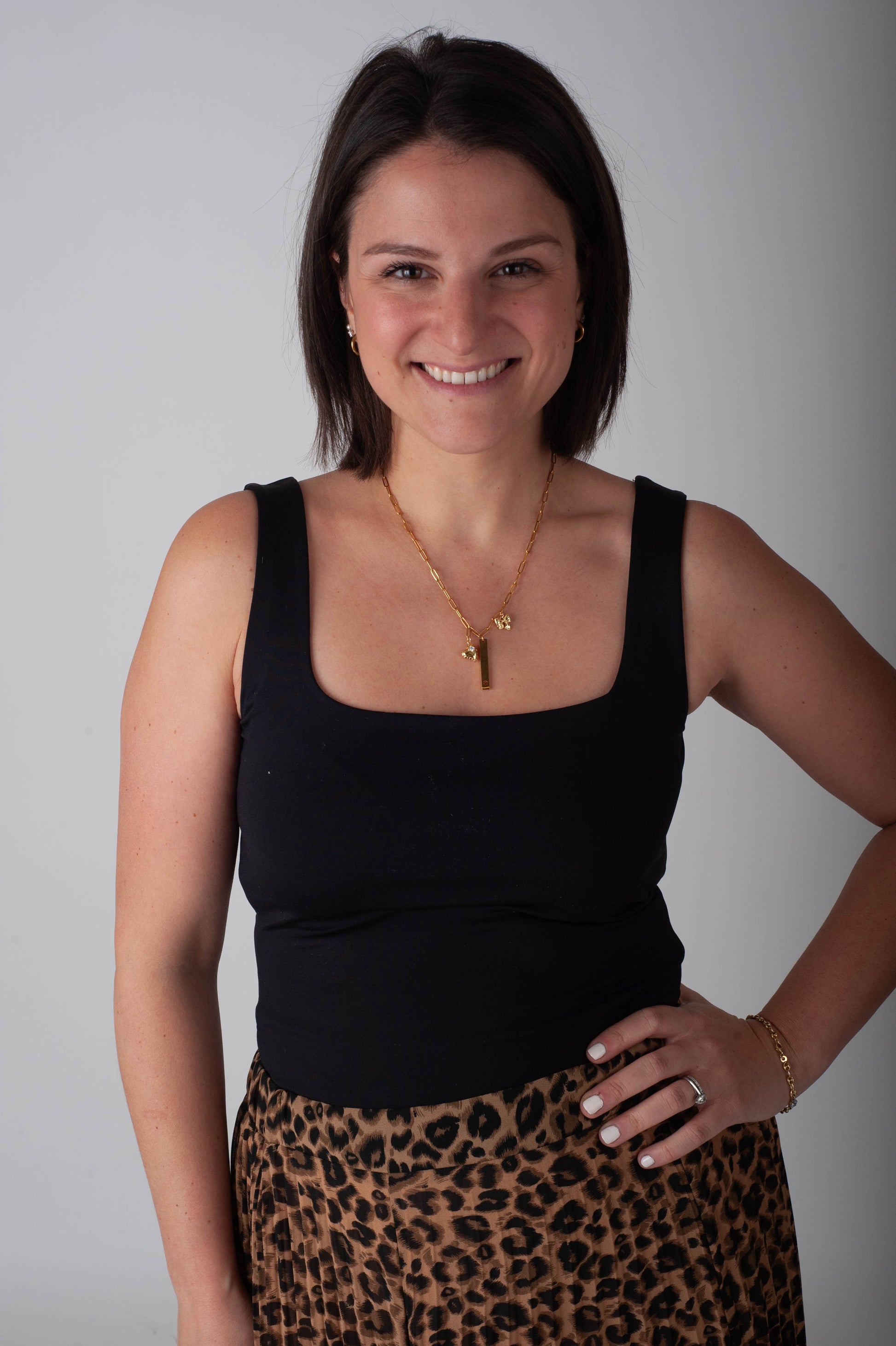 Woman wearing a black top and leopard print skirt against a gray background