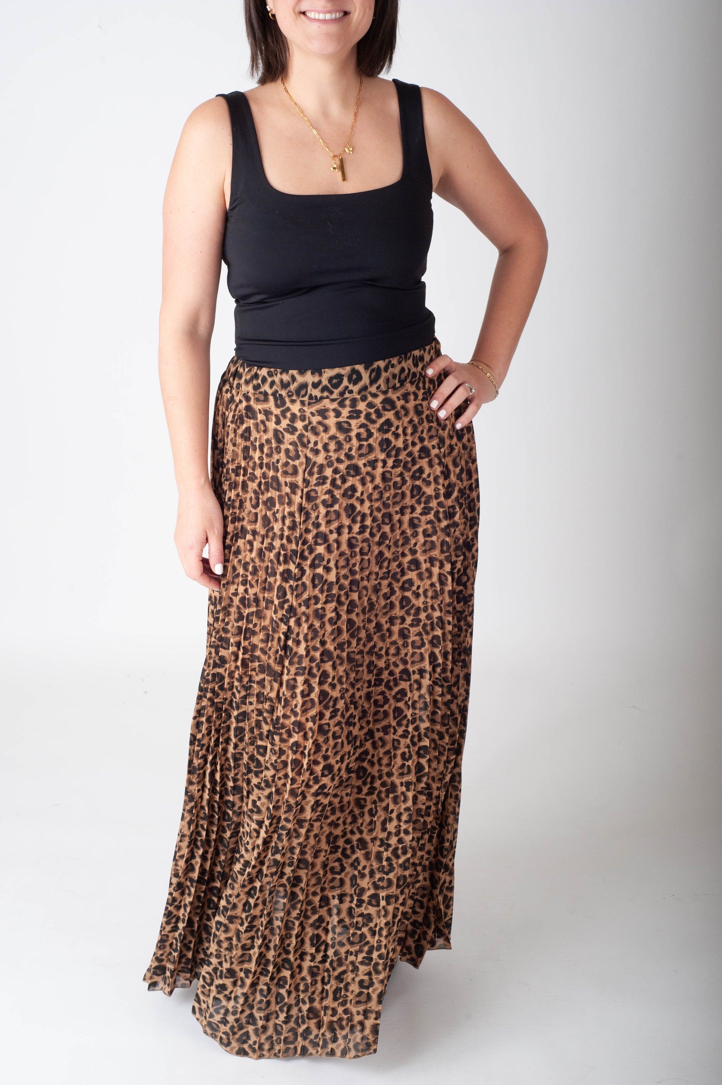Woman wearing a black tank top and leopard print skirt on a white background
