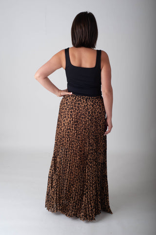 Person wearing a black tank top and leopard print skirt on a plain background