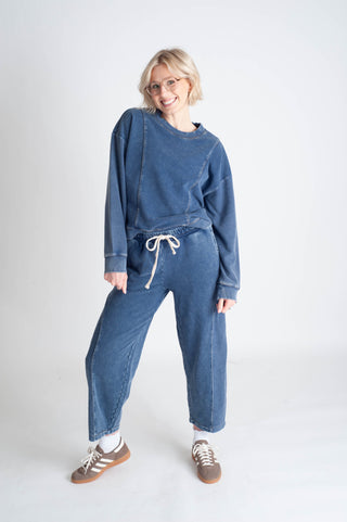 Person wearing a blue outfit with a matching sweater and pants on a white background