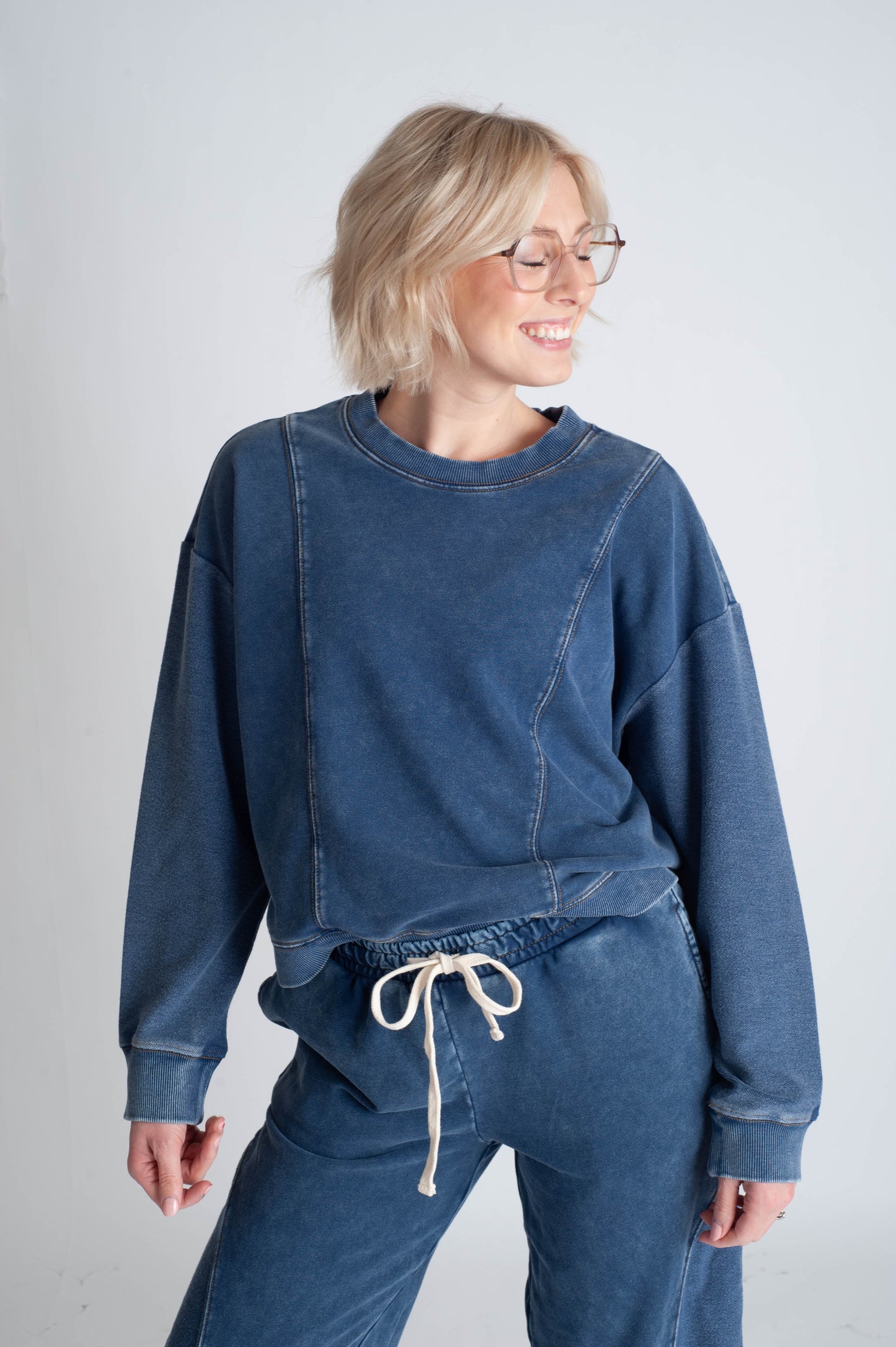 Person wearing a blue sweatshirt and pants set on a plain background