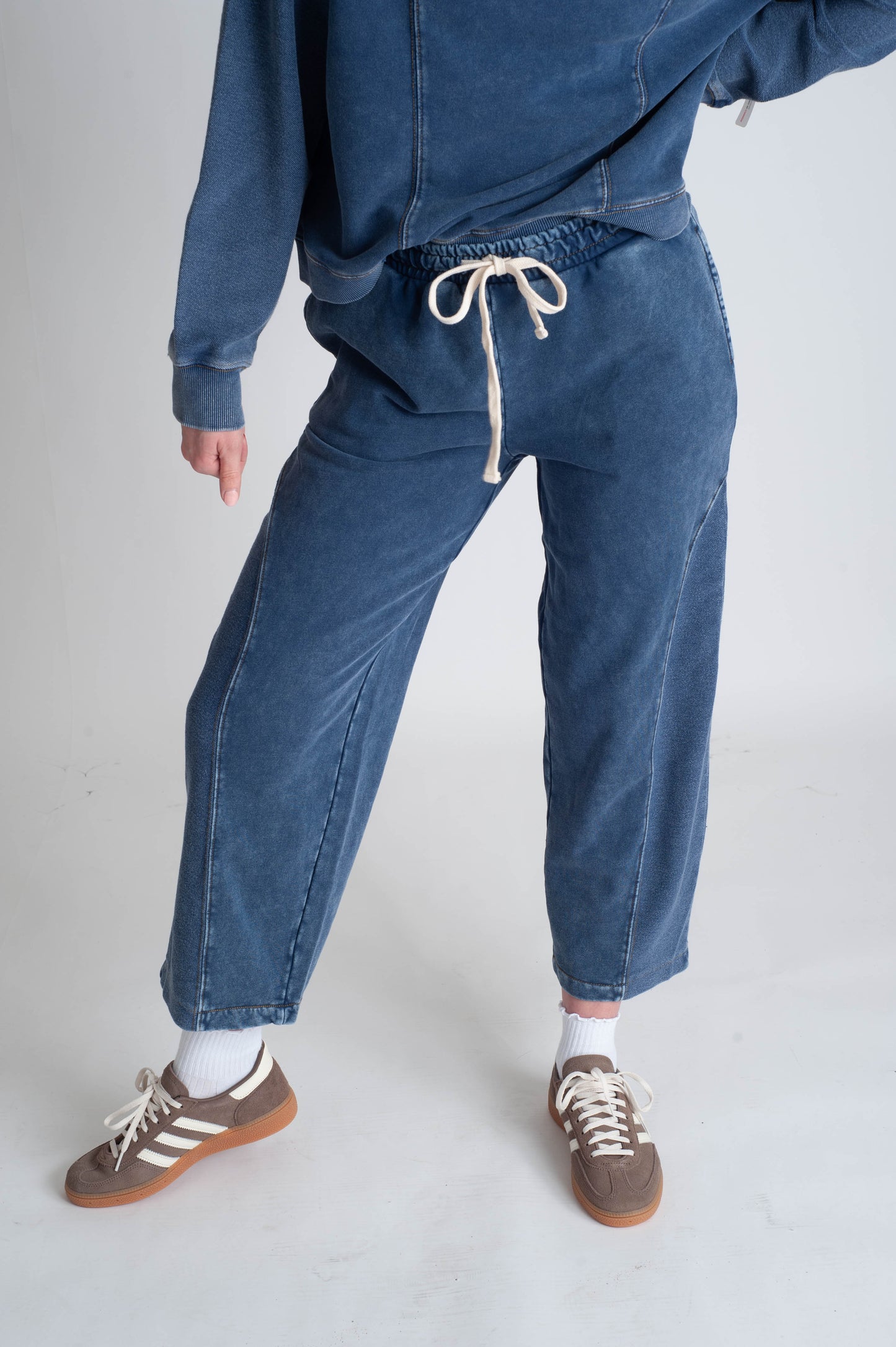 Person wearing a blue denim outfit with jogger pants and a hoodie on a white background