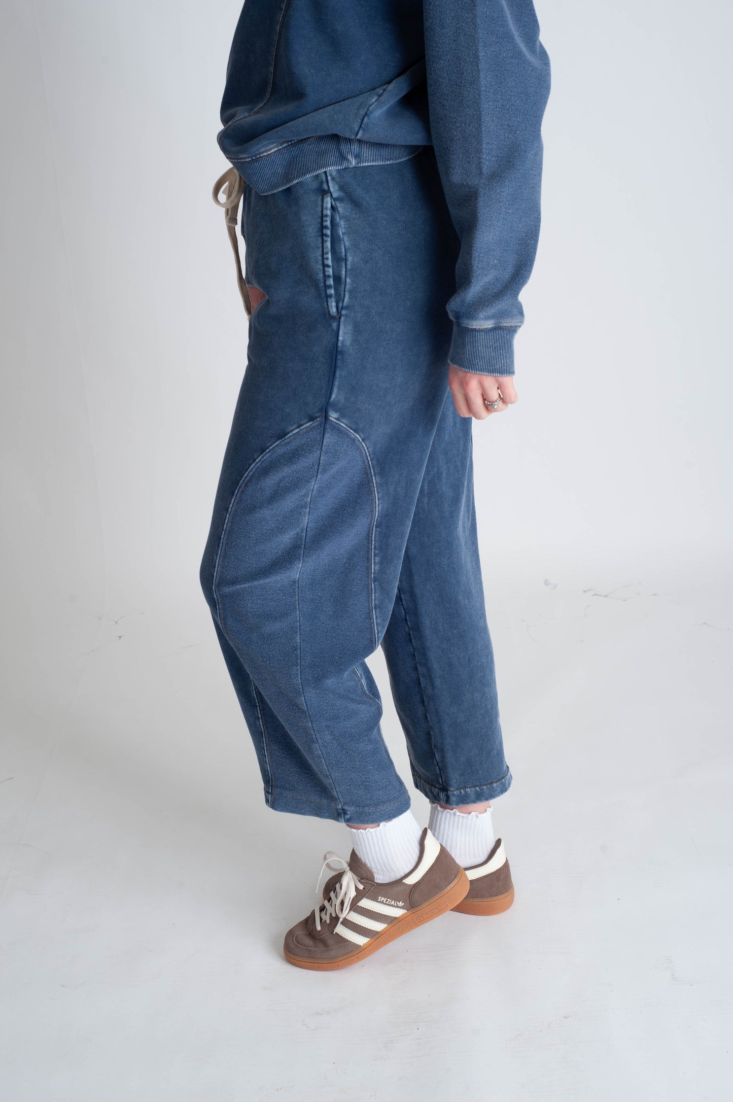 Person wearing blue jeans and a matching jacket on a white background