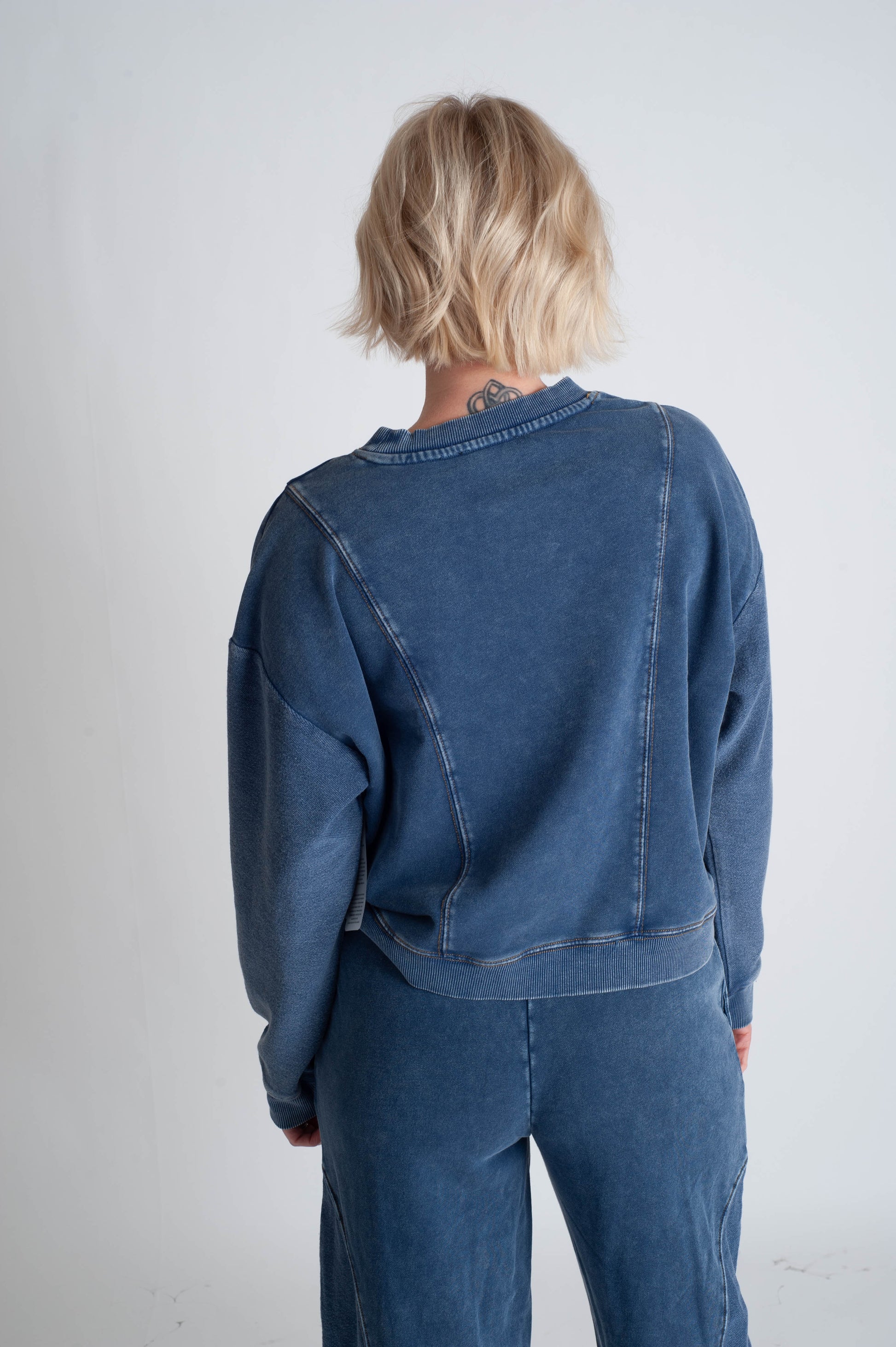 Person wearing a blue denim outfit against a plain background