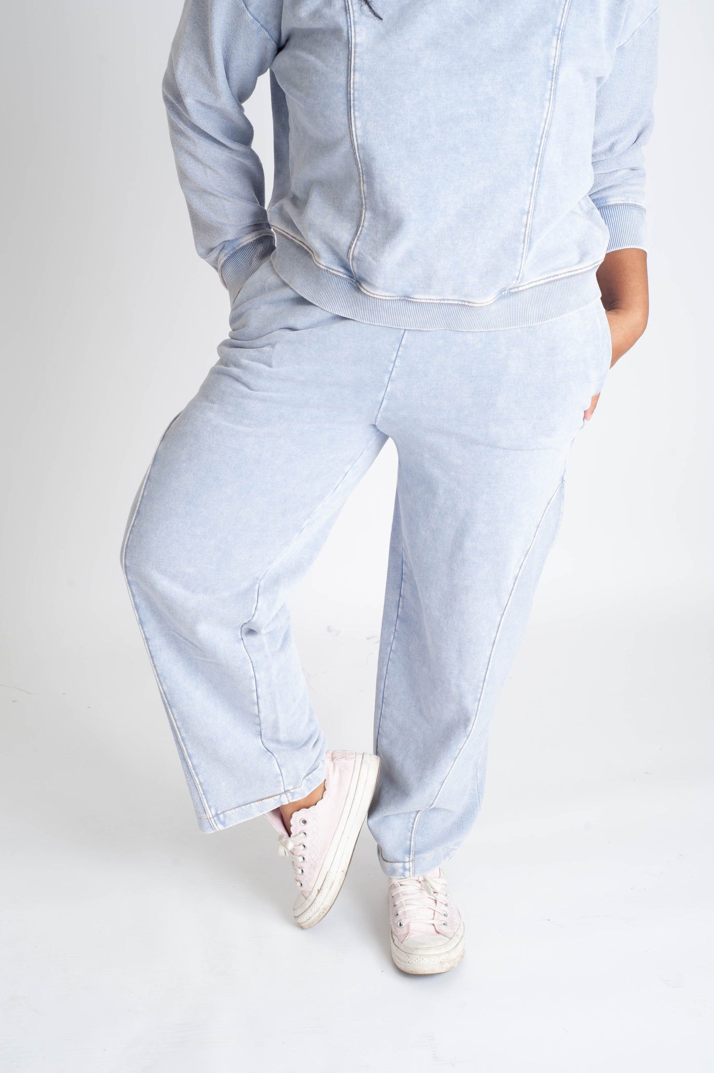 Person wearing light blue denim outfit with white sneakers on a white background