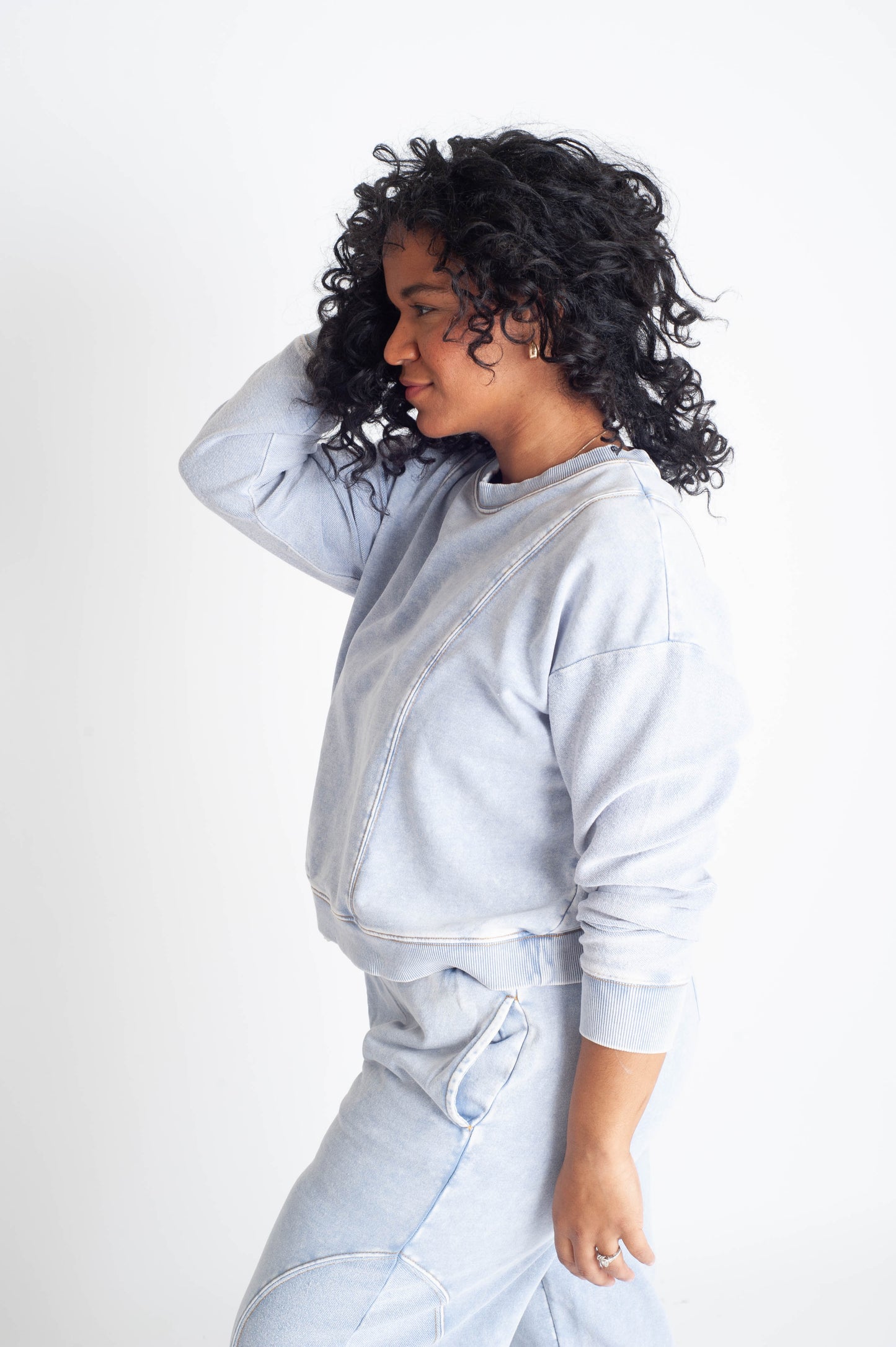Person wearing a light gray sweatshirt and pants on a white background