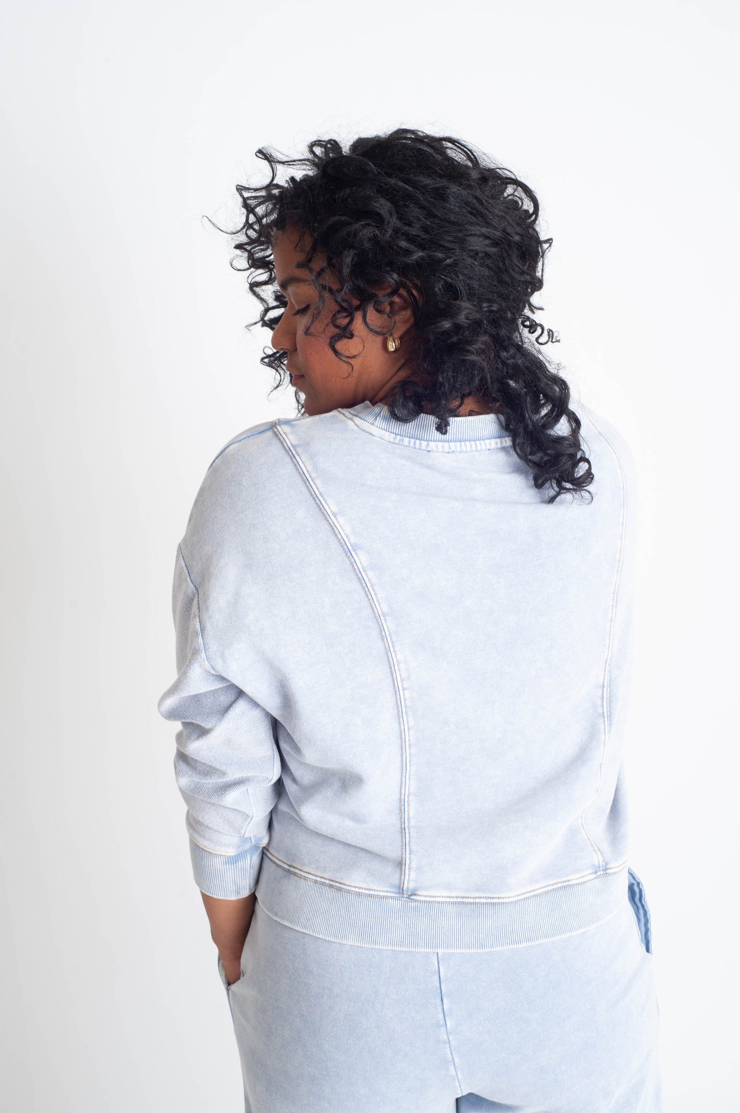 Person wearing a light blue outfit against a white background