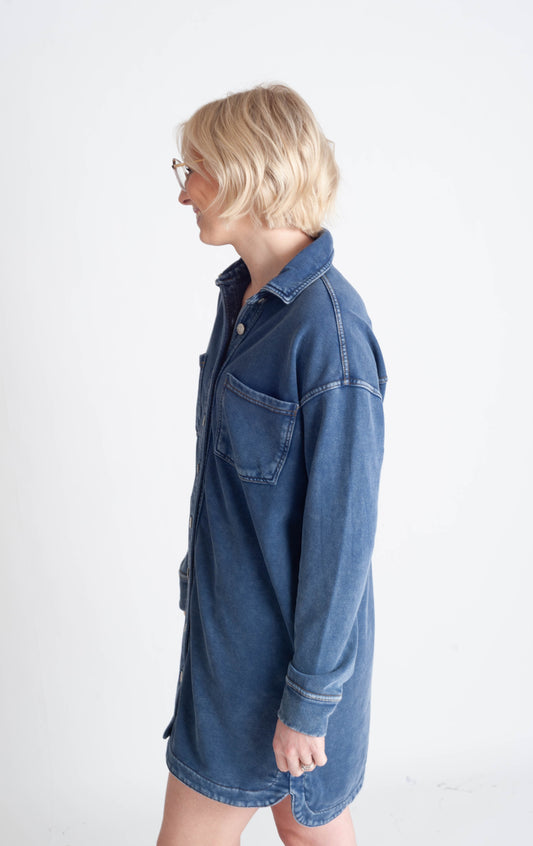 Woman wearing a blue denim shirt dress on a white background