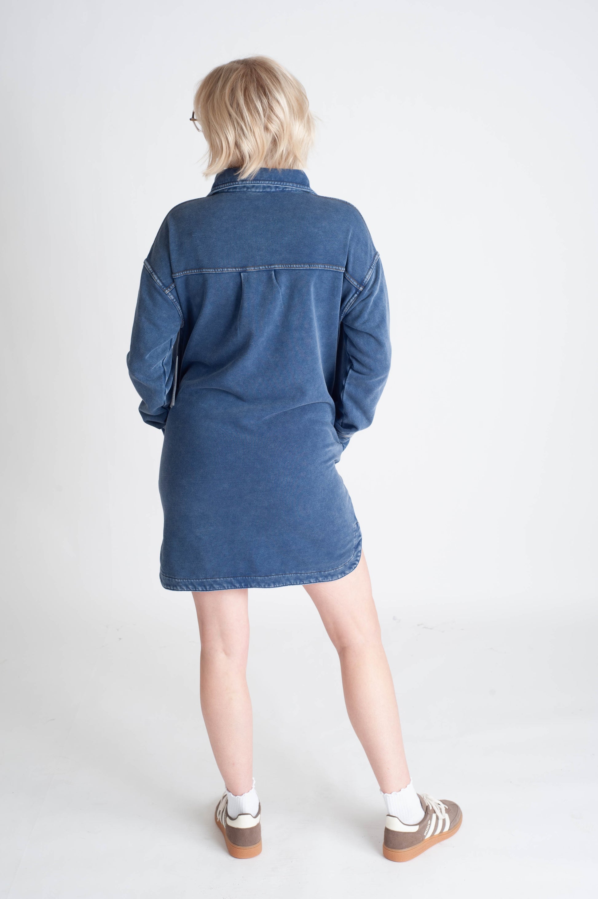 Person wearing a blue denim dress on a white background