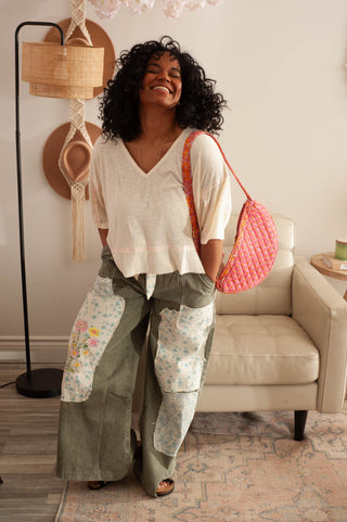 women wearing green patchwork pants nd a white blouse in a living room setting