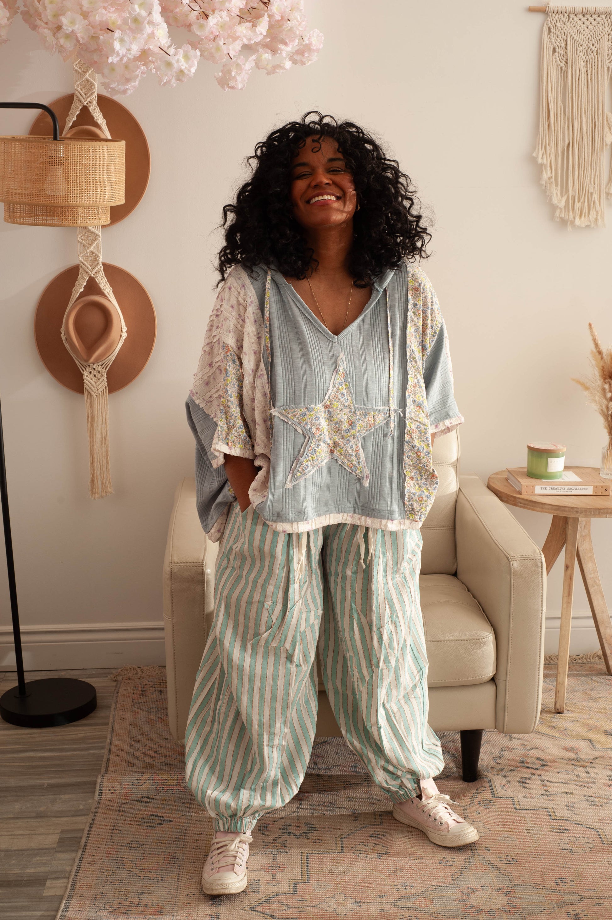 Woman in a light blue top and striped pants standing in a cozy living room.
