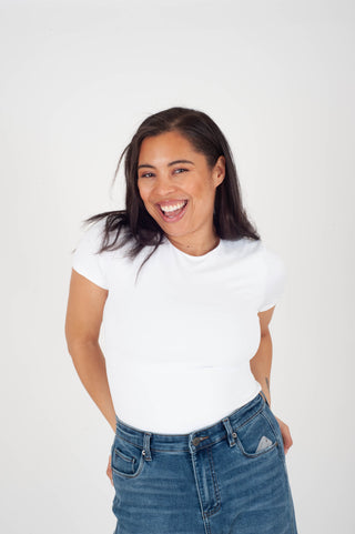 Woman wearing a white t-shirt and blue jeans against a plain background
