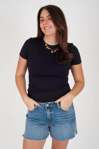 Woman wearing a black t-shirt and blue denim shorts on a white background