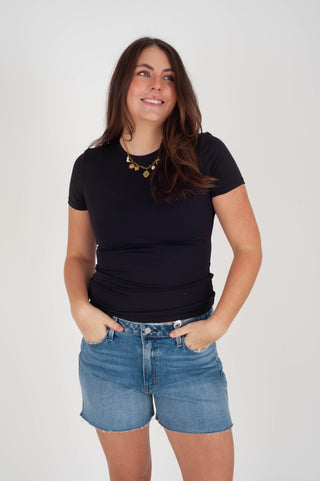 Woman wearing a black t-shirt and blue shorts on a white background