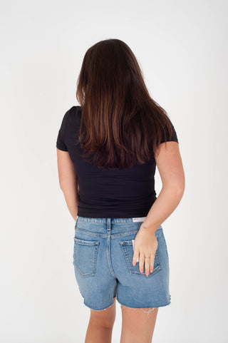Person wearing a black top and blue shorts on a white background