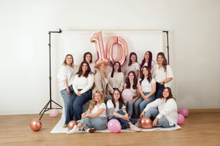 women in front a photo backdrop in white shirts and blue jeans