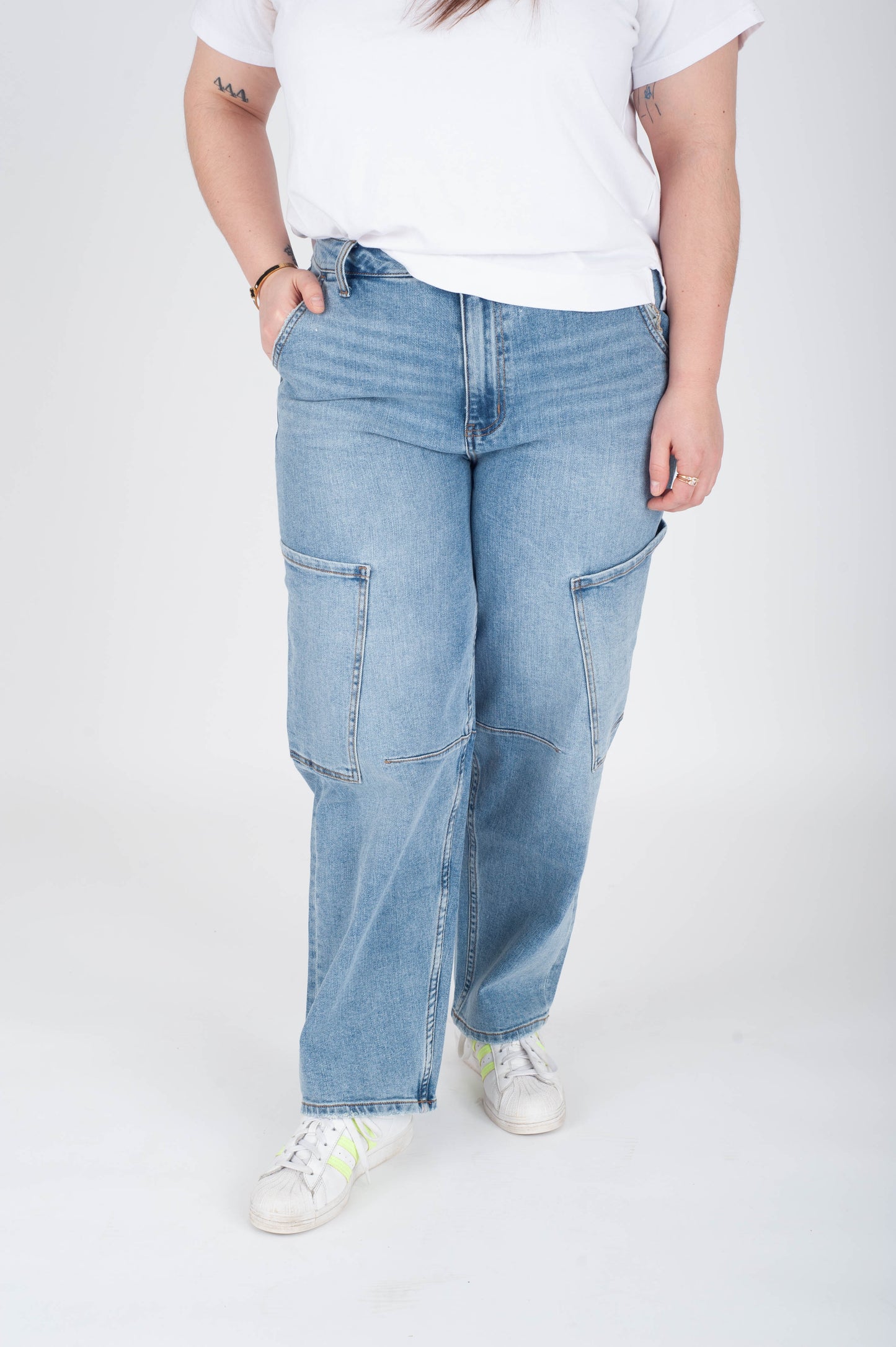 Person wearing light blue jeans and a white t-shirt on a plain background