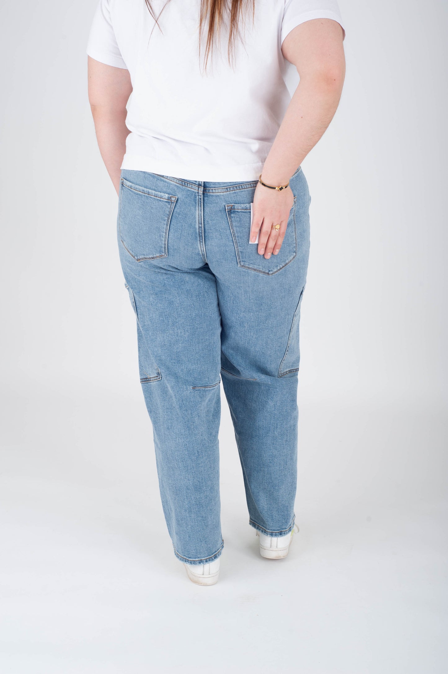 Person wearing light blue jeans and a white shirt on a white background