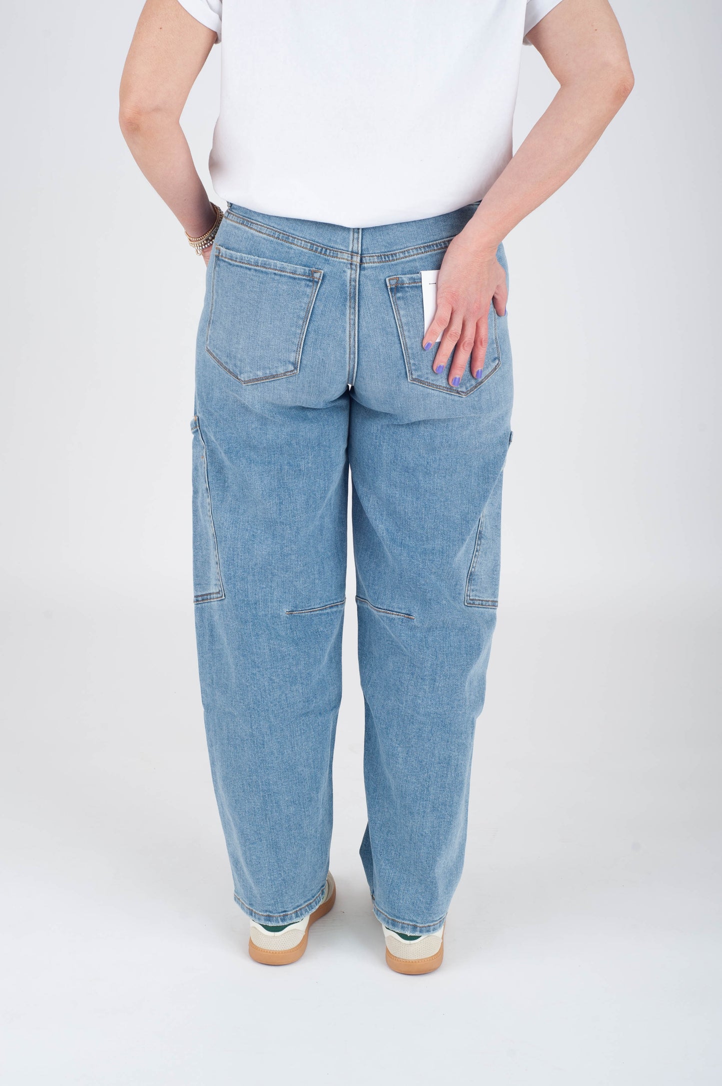 Person wearing light blue jeans and a white shirt on a white background