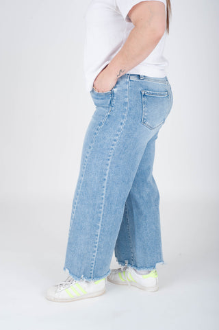 Person wearing light blue jeans and white sneakers on a white background