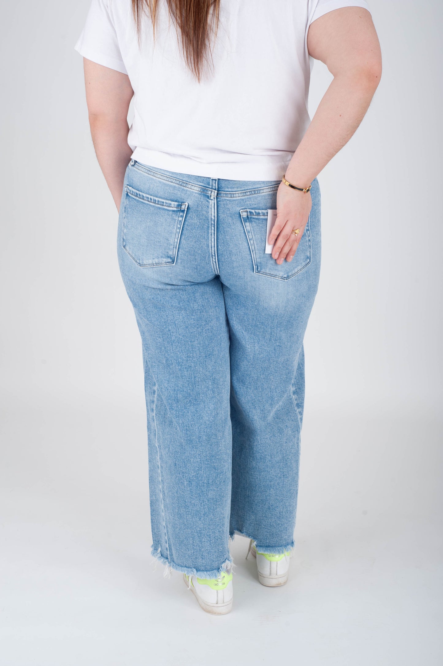 Person wearing light blue jeans and a white shirt on a plain background