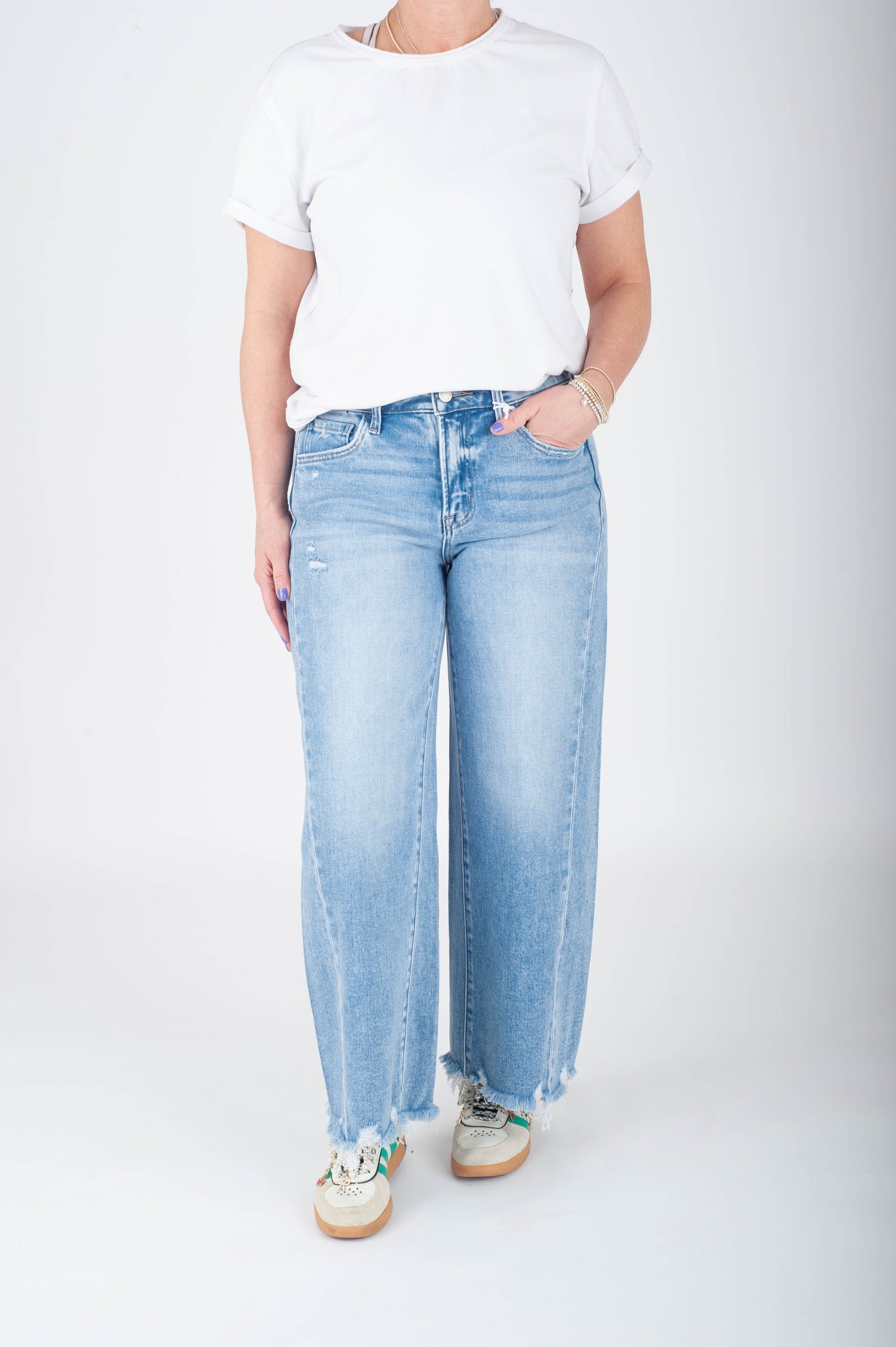Person wearing light blue jeans and a white t-shirt on a plain background