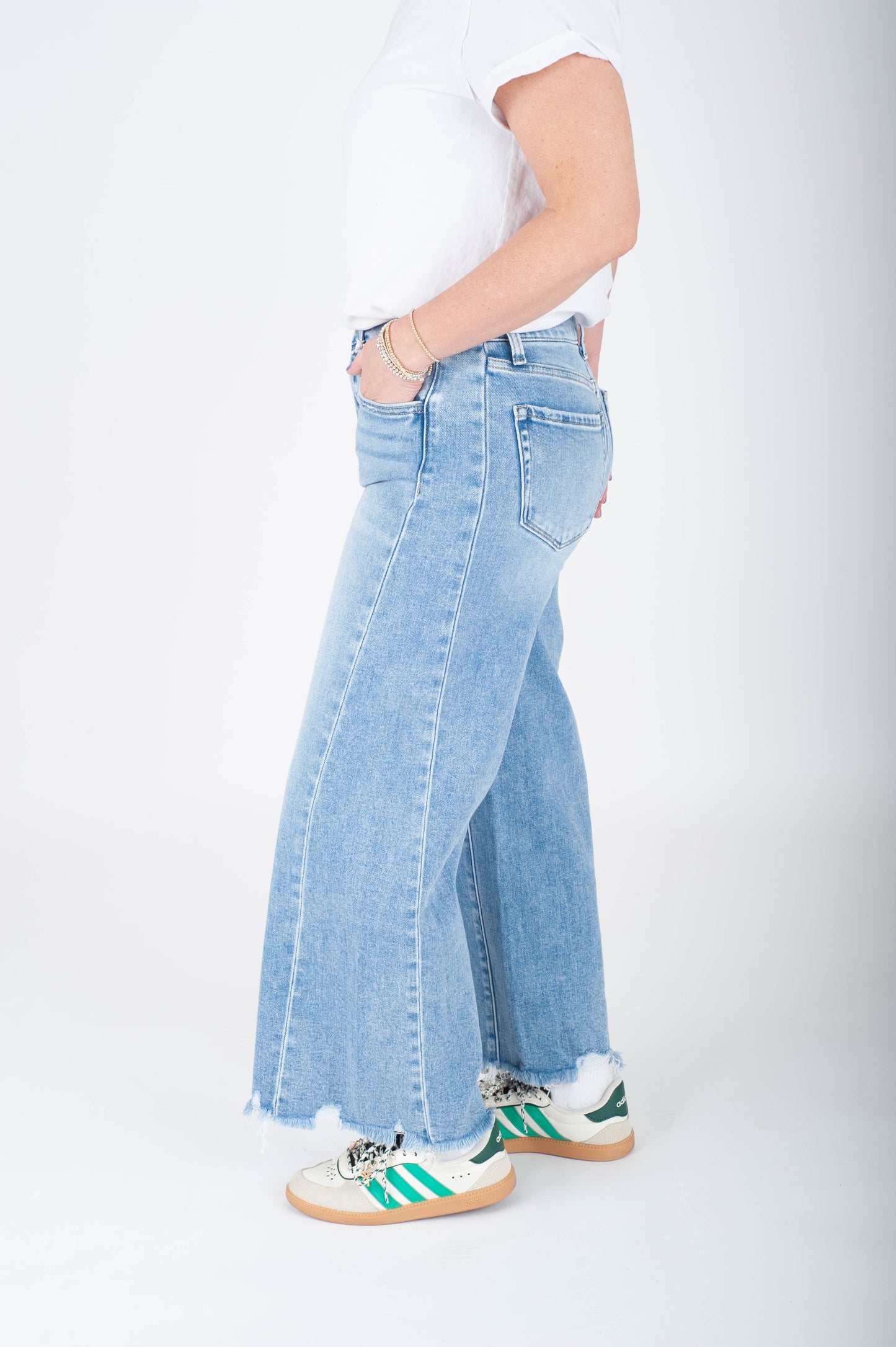 Person wearing light blue jeans and white sneakers on a white background