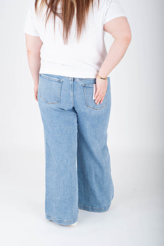 Person wearing light blue jeans and a white shirt on a plain background