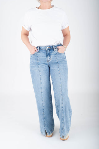 Person wearing light blue jeans and a white t-shirt on a white background