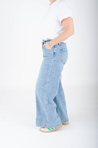 Person wearing light blue jeans and a white shirt on a white background
