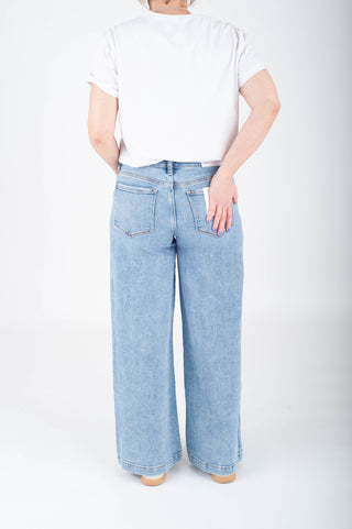 Person wearing light blue jeans and a white t-shirt on a white background
