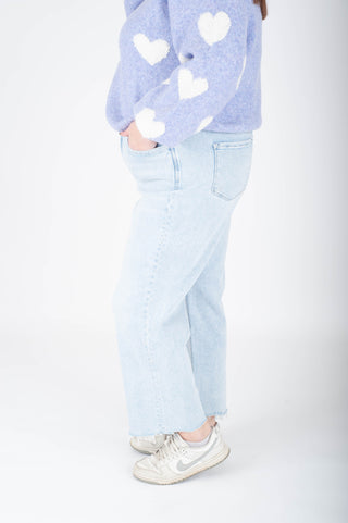 Person wearing a light blue heart-patterned sweater and light blue jeans on a white background