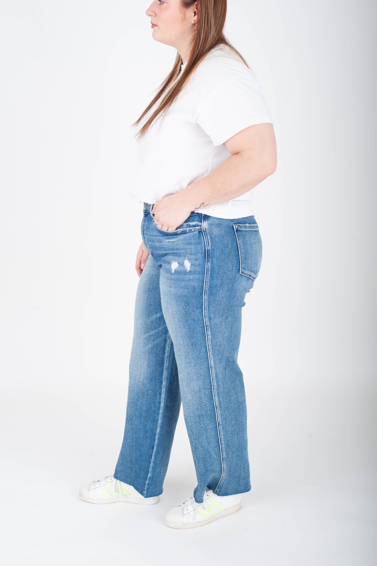 Person wearing blue jeans and a white shirt on a plain background