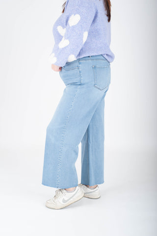Person wearing light blue jeans and a light purple sweater on a white background