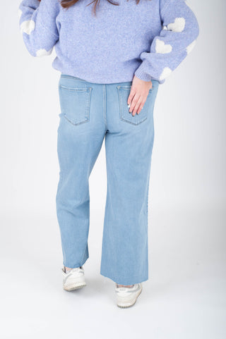 Person wearing a light blue sweater and jeans on a white background
