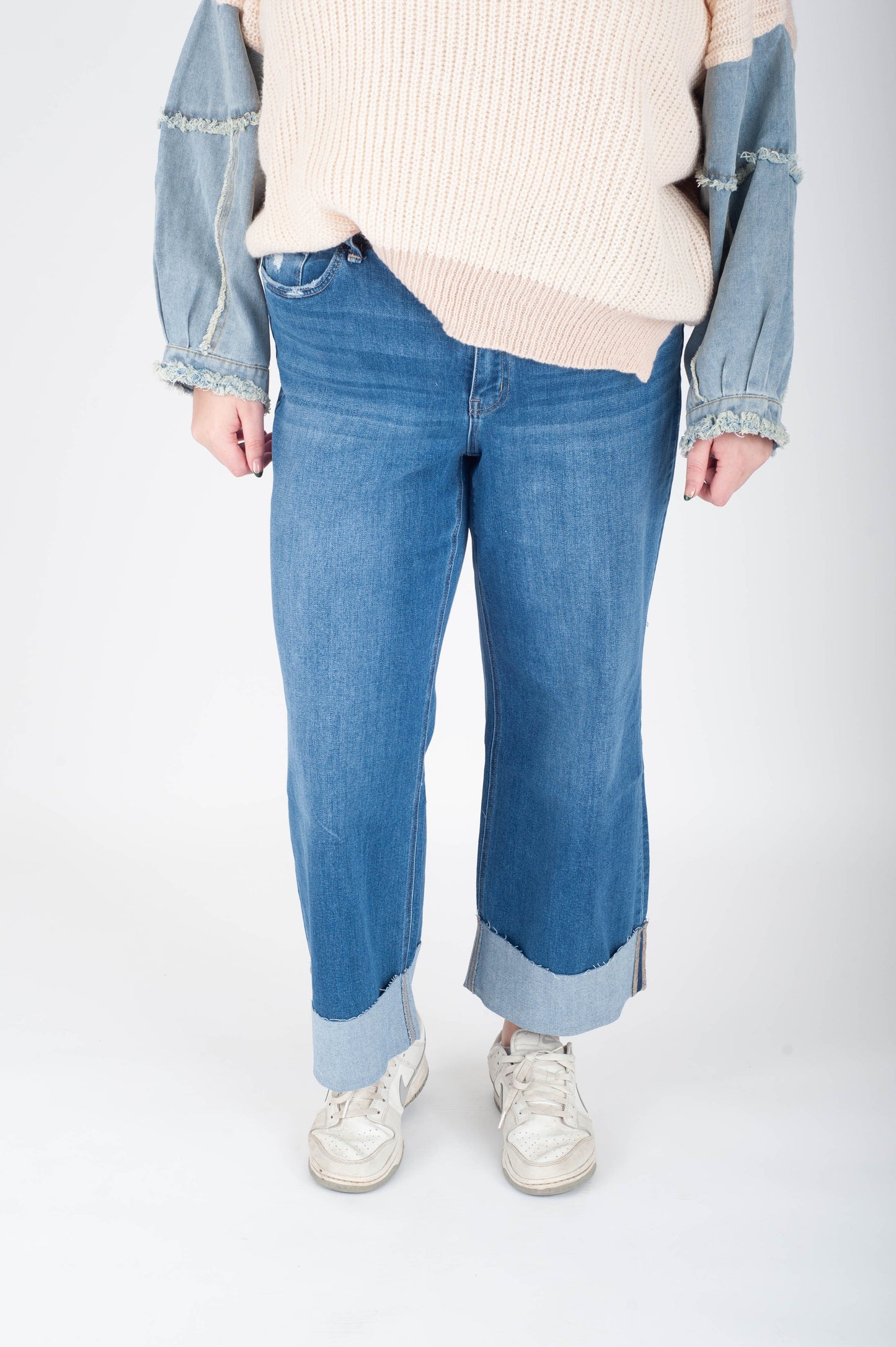 Person wearing blue jeans and a light-colored sweater on a white background