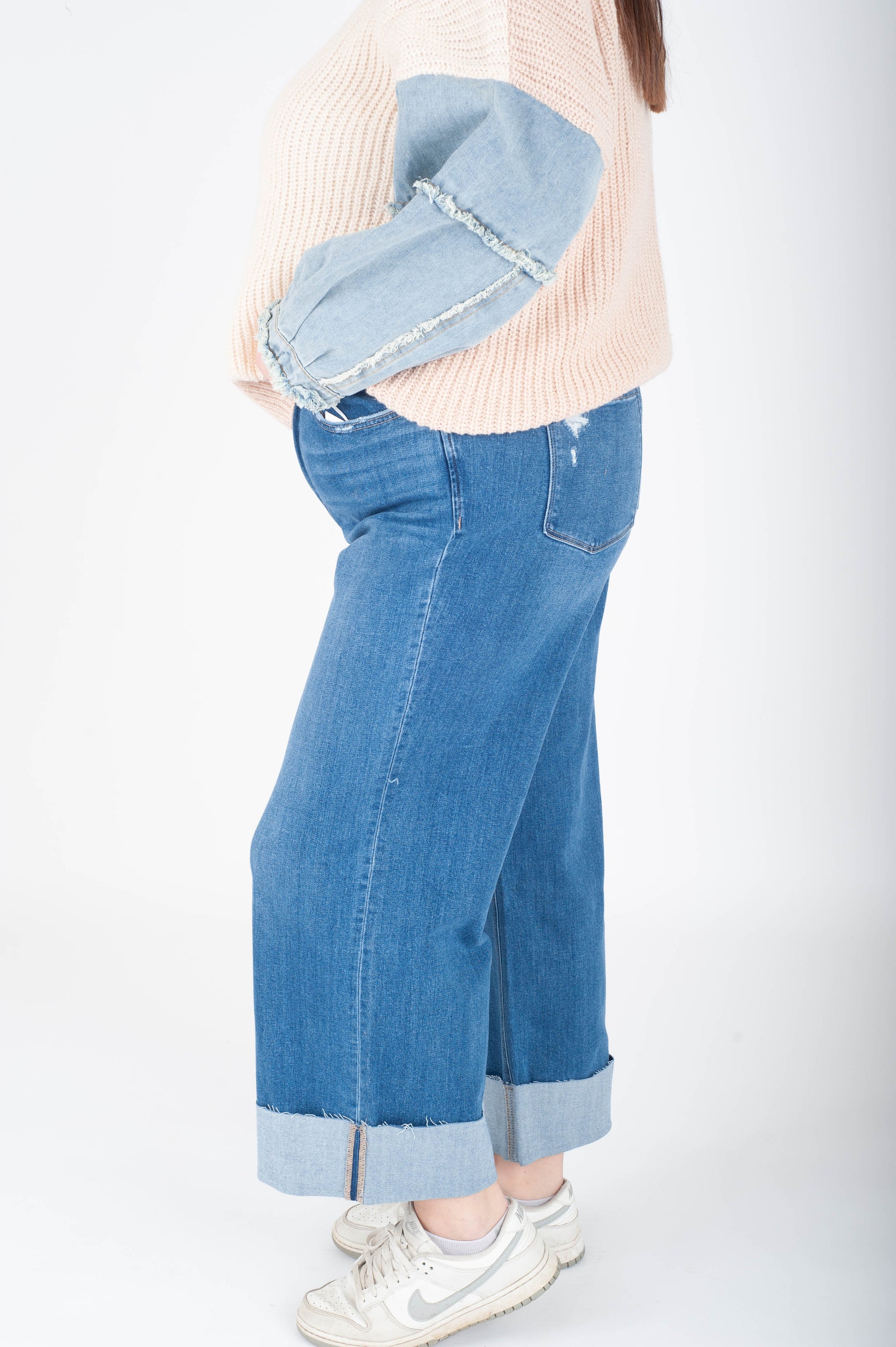 Person wearing blue wide-leg jeans with a white background