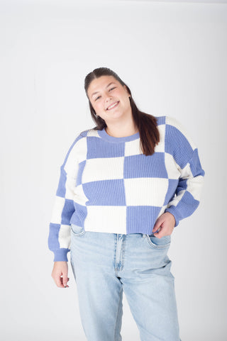 Person wearing a blue and white checkered sweater on a plain background