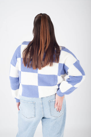 Person wearing a blue and white checkered sweater on a plain background