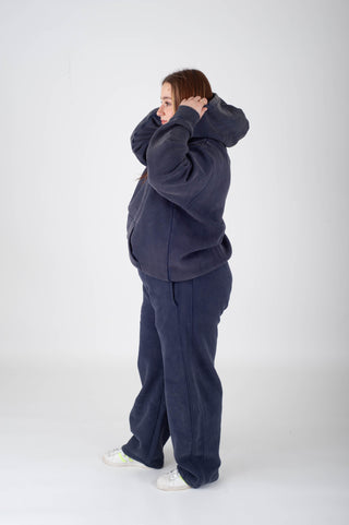 Person wearing a navy blue tracksuit on a white background