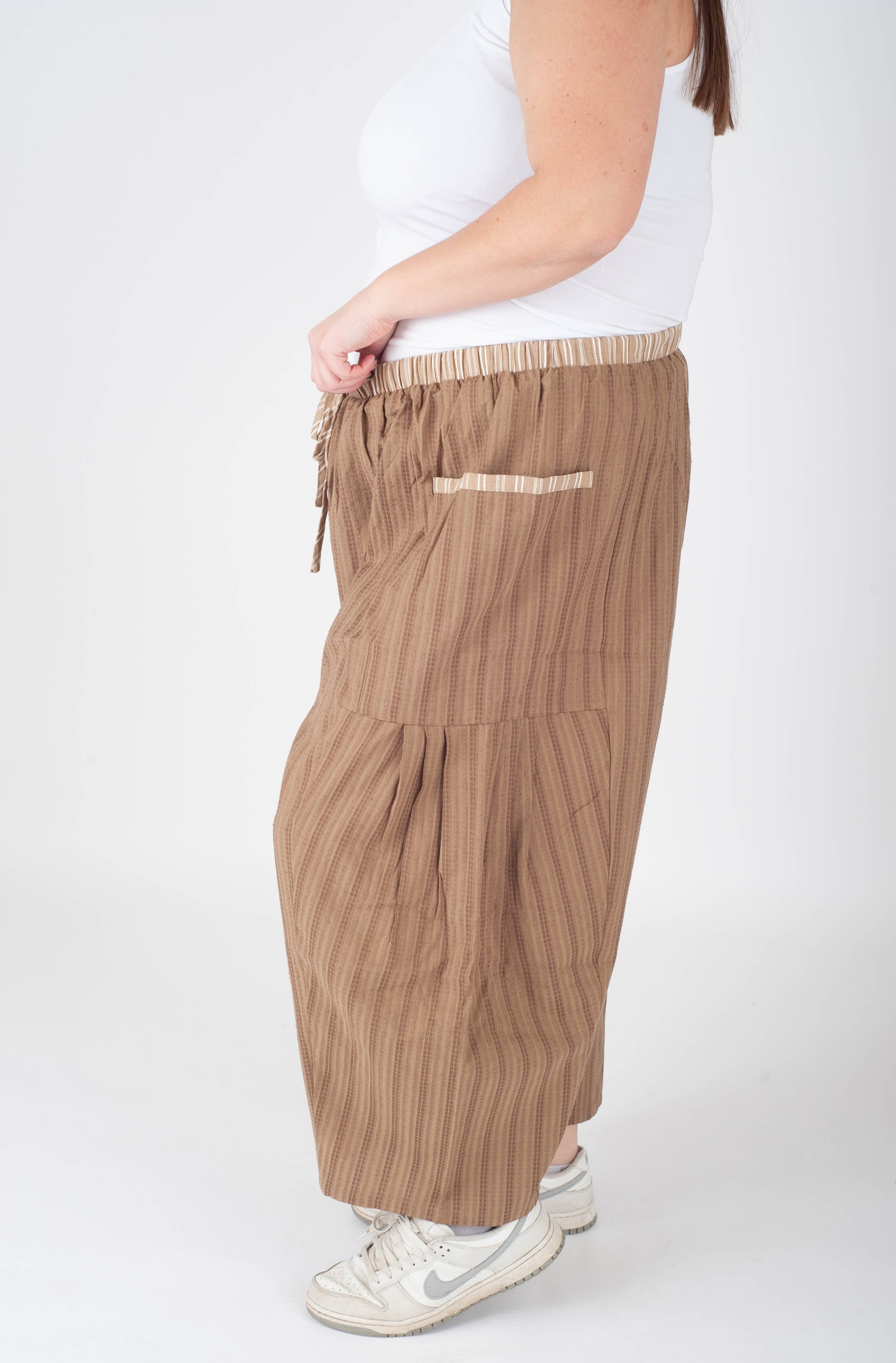 Person wearing beige striped pants on a white background